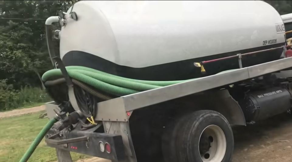 Septic vacuum truck with suction hose connected for a residential septic tank pump-out