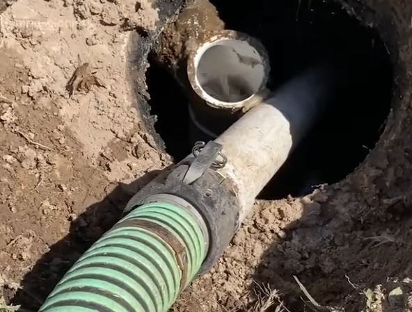 Vacuum hose inserted through an open septic tank lid during pumping